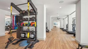 Een sportschool met trainingsapparatuur, een rek met gewichten en een loopband.