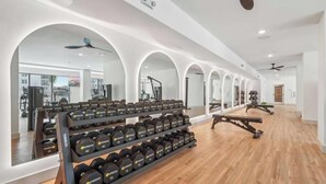 Een sportschool met gewichthefapparatuur, spiegels en fitnessapparaten.