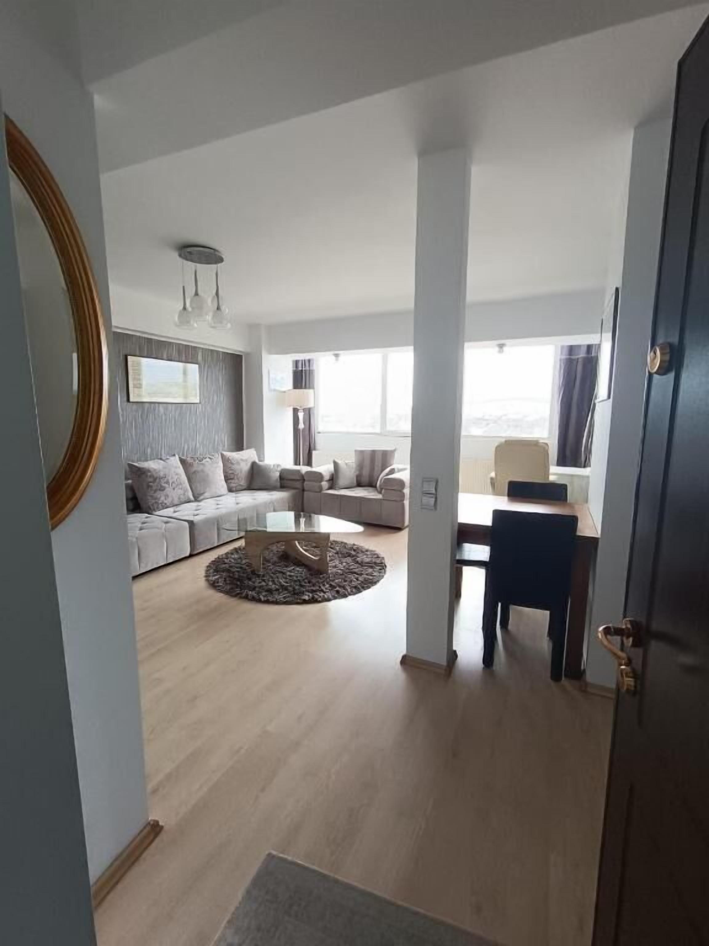 Uma sala de estar moderna com um sofá, mesa de centro e uma porta que dá para outro cômodo.