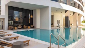Un hotel moderno con piscina, sedie a sdraio e un design d'interni contemporaneo.