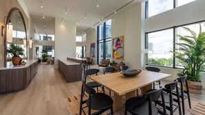 Una cucina moderna con isola centrale, zona pranzo con tavolo in legno e sedie nere, e ampie finestre che offrono vista sulla città.