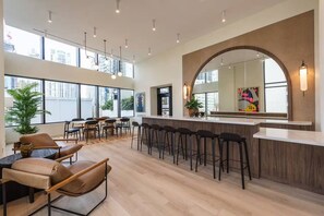 Un interior moderno con una zona de bar, asientos y grandes ventanales.