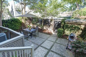 A patio with a table and chairs, a hanging umbrella, and a stone wall. - The Williams House of 1816 | Courtyard + Parking (Savannah)