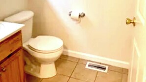 A bathroom with a toilet, a wooden cabinet, a window, and a towel rack.