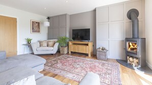 Ein modernes Wohnzimmer mit einer Couch, Fernseher, Kamin und dekorativen Teppichen.