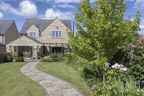 A stone house with a paved driveway leading to a garage. - Beautiful 4 Bed 3 Bath Cotswold Home with Hot Tub (Cheltenham)