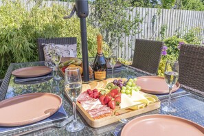 A table set outdoors with a charcuterie board, wine glasses, and a bottle of Canti Prosecco. - Beautiful 4 Bed 3 Bath Cotswold Home with Hot Tub (Cheltenham)