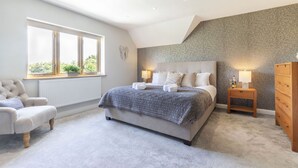 Ein Schlafzimmer mit Bett, Stuhl, Kommode, Fenster und Lampe.