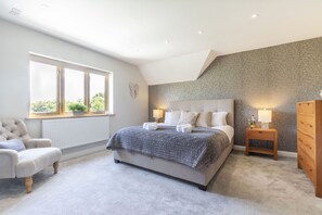 A bedroom with a bed, a chair, a dresser, a window, and a lamp. - Beautiful 4 Bed 3 Bath Cotswold Home with Hot Tub (Cheltenham)