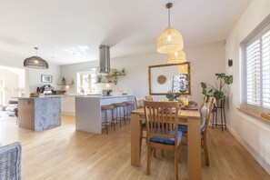 Une cuisine moderne dotée d’un îlot central, de tabourets de bar et de luminaires suspendus.