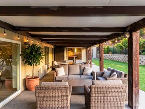 An outdoor patio with wicker furniture, a potted plant, and string lights. - Saltwater Pool, Billiards, Arcade, Sleeps 12 (San Diego)