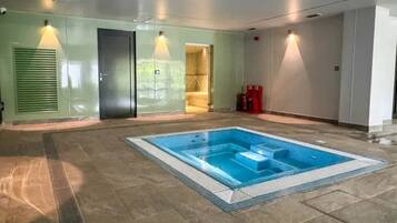 An indoor swimming pool with a tiled floor, a door, and a wall with a textured pattern.