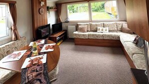 Un interior acogedor de autocaravana con una mesa de comedor, zona de estar y televisor.