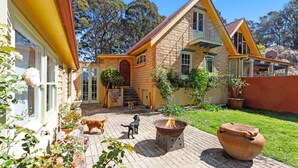 A stone house with a brick patio, a fire pit, and two dogs. - Petana Farm Stay - Pet-friendly Country Retreat (Morton)