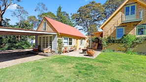 A two-story house with a covered patio, a front yard, and a garden area.