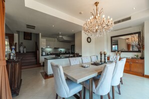 Ein großzügiger Essbereich mit einem großen Tisch und Stühlen, einer Chandelier und Blick auf die Küche und die Treppe.