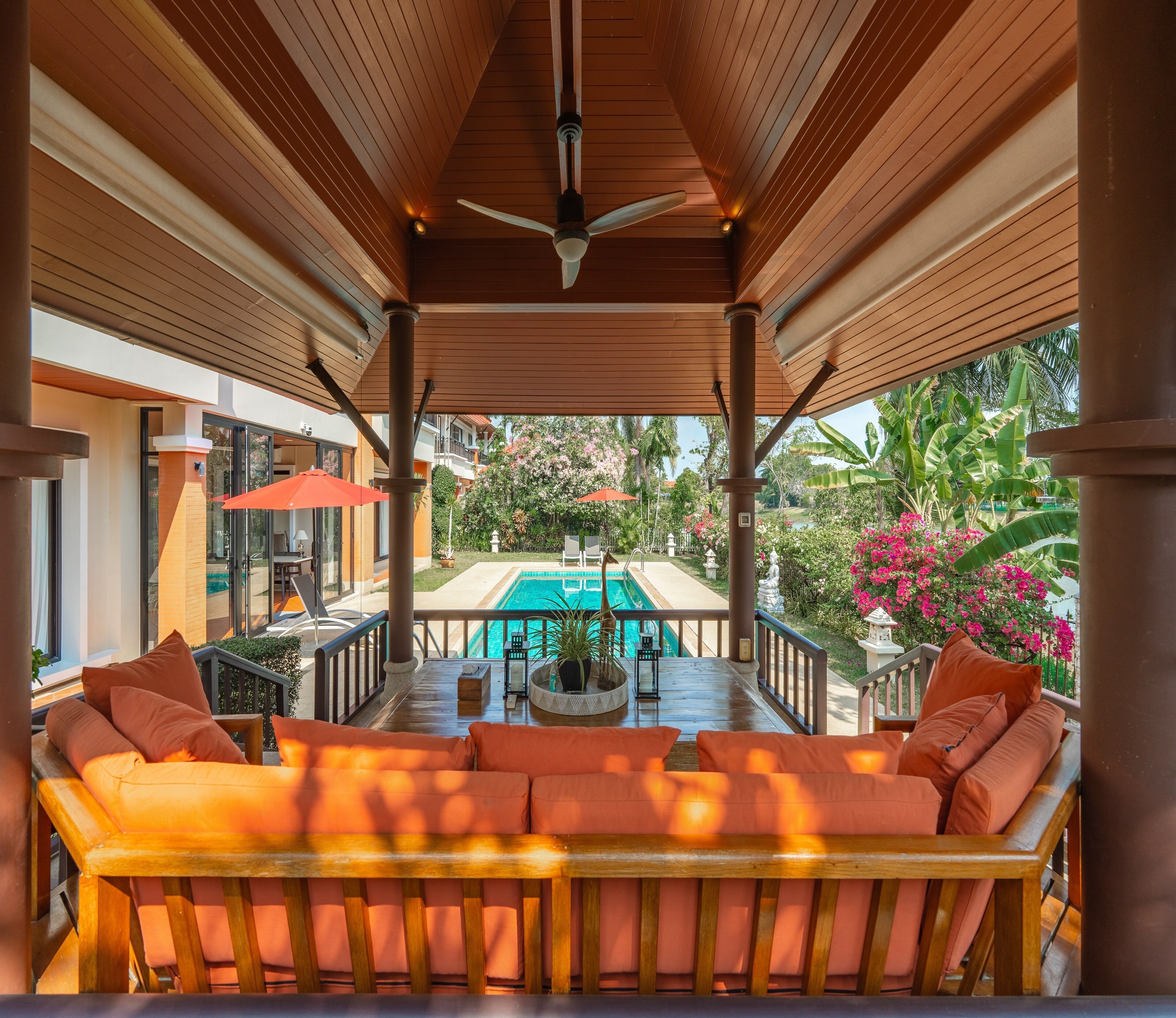A covered outdoor seating area with a pool in the background.