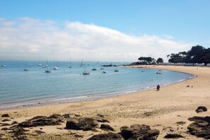 Una playa con barcos, una orilla arenosa y una zona rocosa.