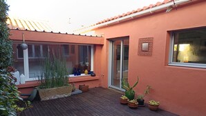 Une terrasse avec des plantes en pot, une fenêtre et une porte.