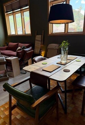 A room with a wooden table, chairs, a sofa, a lamp, and a guitar. - The Western View: Pool, Hot Tub, Ski, Repeat (Telluride)