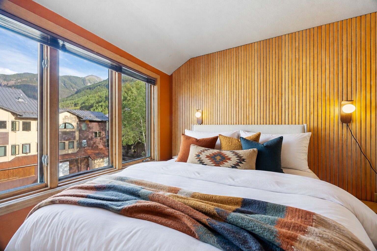 Ein Hotelzimmer mit einem großen Bett, Blick auf Berge und einer Holzvertäfelung.