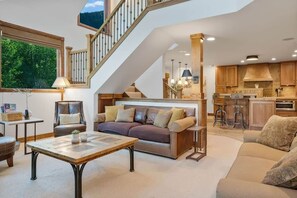 A spacious living area with a sofa, coffee table, and a staircase leading to an upper level. - Ski, Hike & Unwind — Heart of Telluride — 3bd/3ba (Telluride)