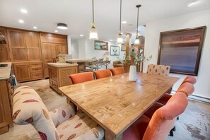 A dining area with a wooden table, orange chairs, and pendant lights. - Ski, Hike & Unwind — Heart of Telluride — 3bd/3ba (Telluride)