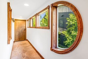 A hallway with a wooden door, a large window with a view of greenery, and a tiled floor. - Ski, Hike & Unwind — Heart of Telluride — 3bd/3ba (Telluride)