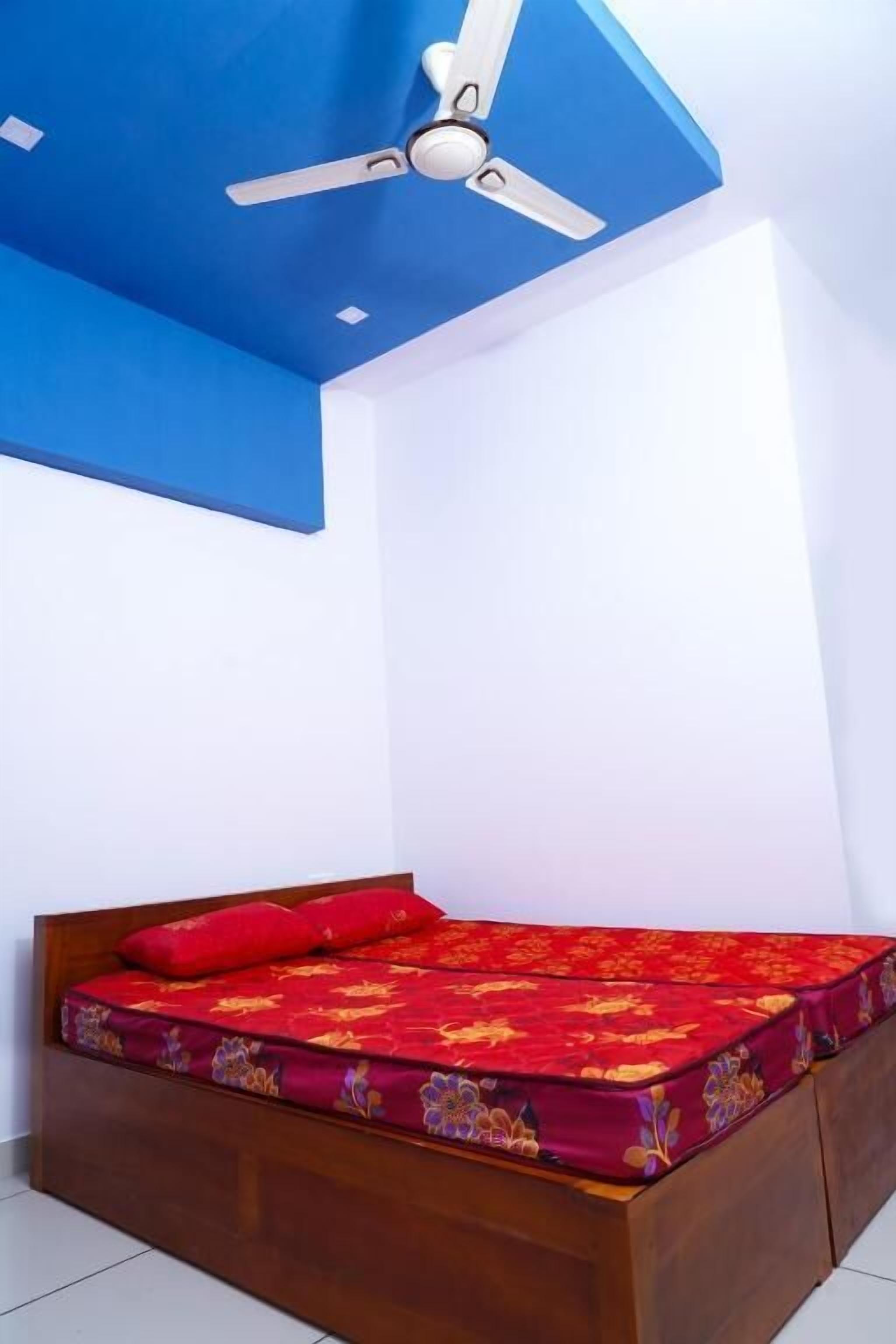 A room with a bed, a ceiling fan, and a blue ceiling.