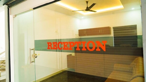 Zona de recepción con puerta de vidrio, ventilador de techo y un letrero que dice 'RECEPTION'.