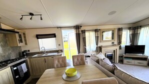 Interior compacto de una caravana con comedor, kitchenette y zona de estar.