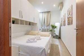 Ein Schlafzimmer mit Bett, Schreibtisch, Stuhl und Heizkörper.