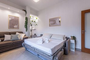 Een moderne slaapkamer met een bed, een slaapbank, een nachtkastje en een wandplank met planten.