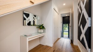 A hallway with a white console table, a potted plant, and a door leading to another room. - Pet Friendly - The Viewpoint, Port Melbourne (Port Melbourne)