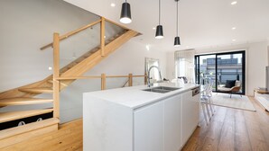 A modern kitchen with a wooden staircase, a large island, pendant lighting, and a view to the outside. - Pet Friendly - The Viewpoint, Port Melbourne (Port Melbourne)