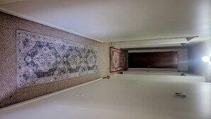 A hallway with a large patterned rug, a smaller rug, and a light fixture.