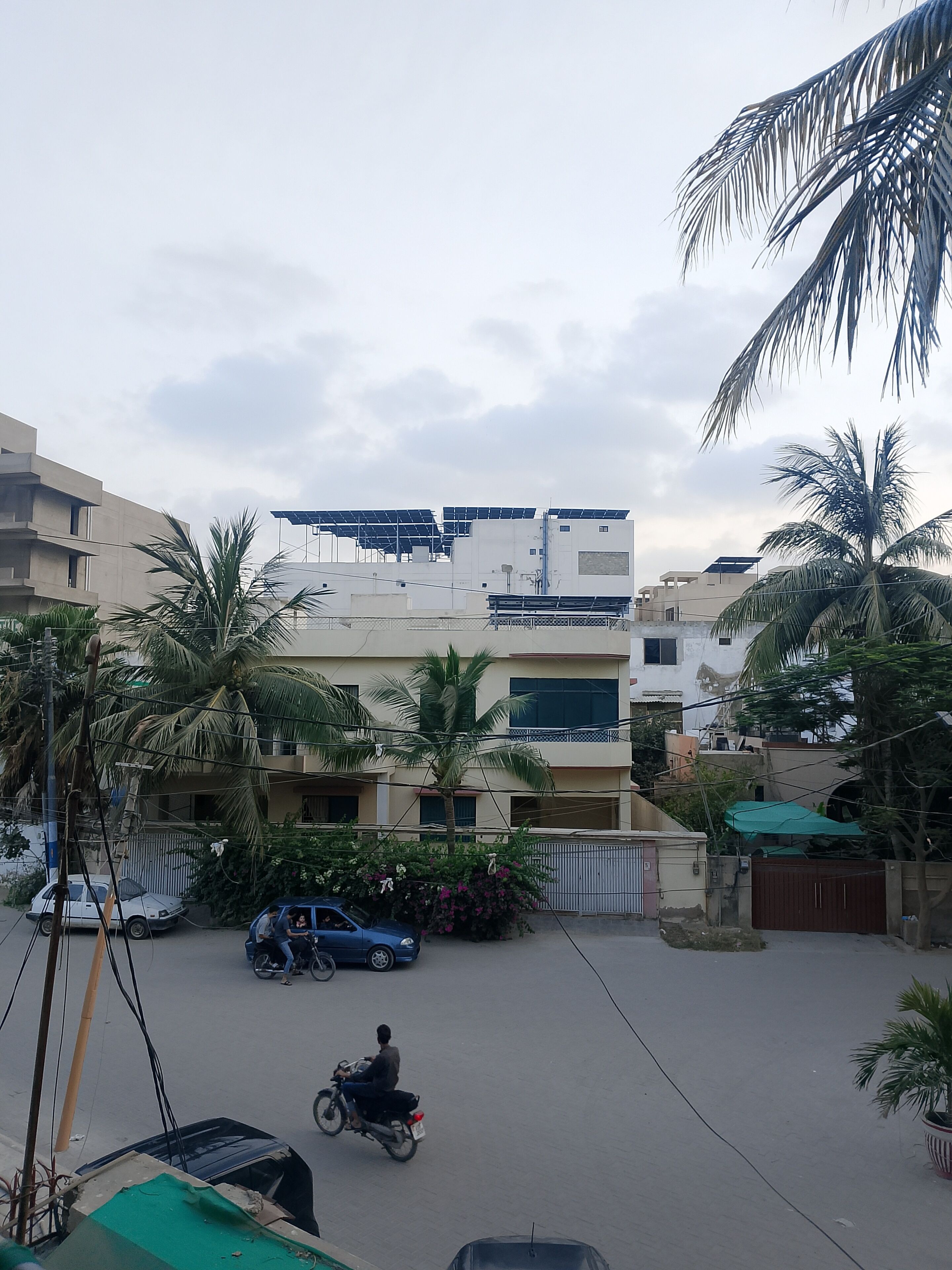 A residential area with buildings, a parked car, and a motorbike.