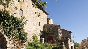 Un bâtiment en pierre avec une porte rouge et une pancarte indiquant la présence d’un robinet.