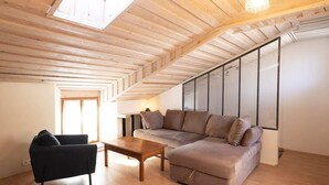 Une pièce de style loft avec un plafond en bois, un canapé, un fauteuil et une petite table.