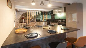 Une cuisine moderne dotée d’un îlot central, d’appareils électroménagers intégrés et d’un coin repas avec des chaises et une table dressée pour le repas.