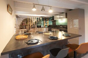 Eine moderne Küche mit Kochinsel, integrierten Geräten und einem Essbereich mit Tisch und Stühlen, gedeckt für eine Mahlzeit.