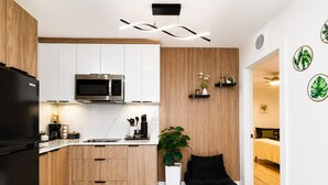 Una cocina moderna con microondas integrado, armarios de madera, encimera negra y un pequeño comedor con un banco negro.
