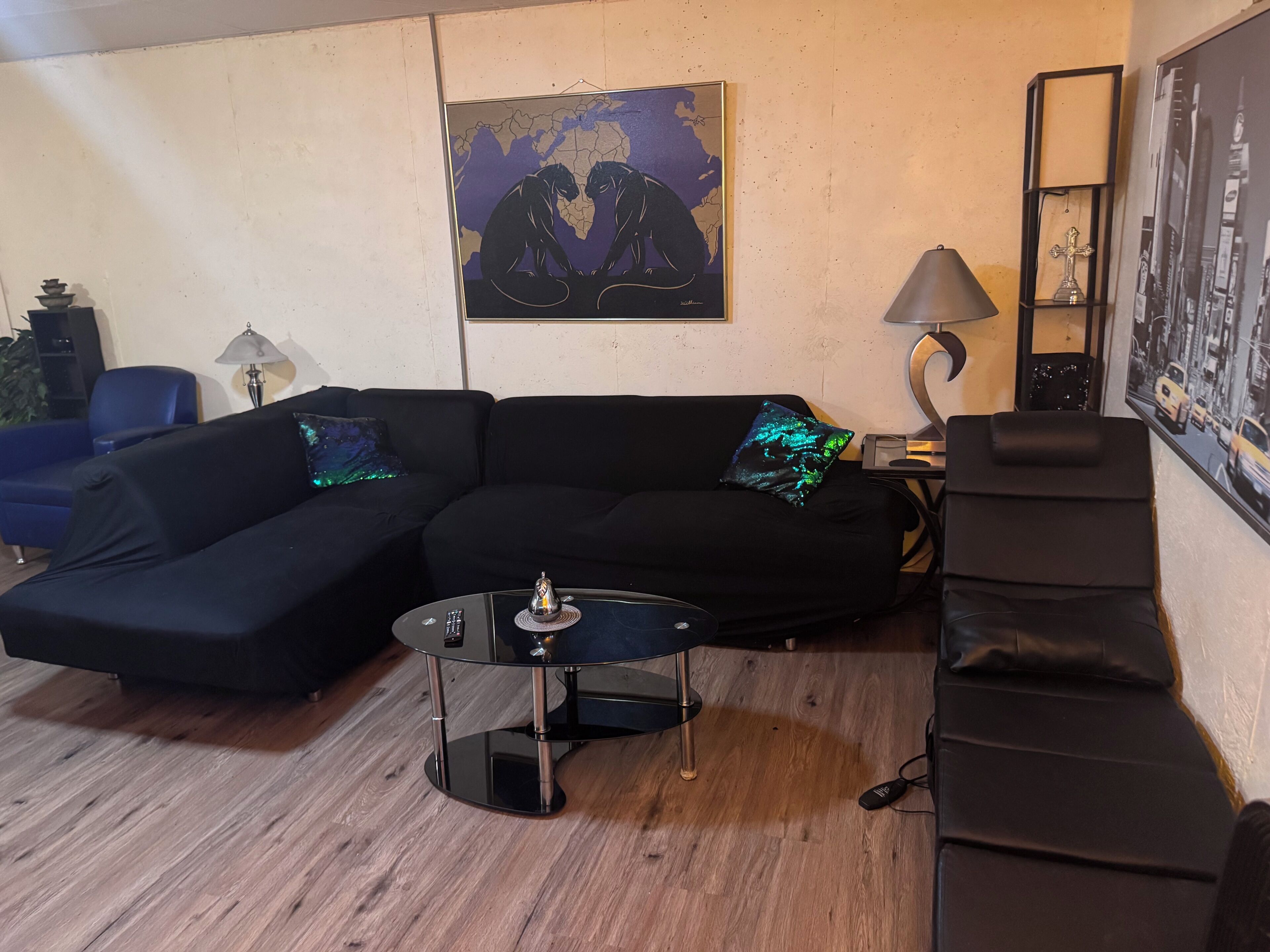 A living room with a sectional sofa, a round coffee table, a lamp, and a framed world map on the wall.