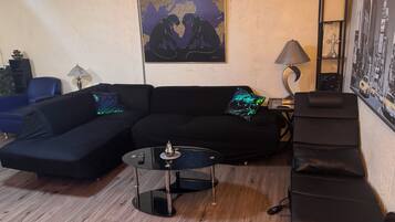 A living room with a sectional sofa, a round coffee table, a lamp, and a framed world map on the wall.