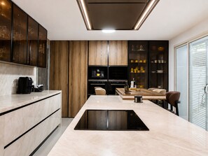 Eine moderne Küche mit einer zentralen Kochinsel, eingebauten Geräten und Holzschränken.
