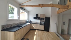 Una cocina con armarios de madera, encimera negra, horno empotrado y refrigerador.