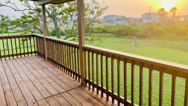 A wooden deck with a railing, a grassy yard, and houses in the background. - Sargent Sunset & Fishing Retreat (Bay City)