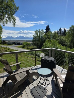 En terrass med utemöbler, utsikt över ett bergigt landskap och en klar himmel.