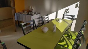 A dining area with a table and chairs, a teapot, and a tray with cups and plates.