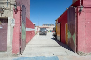 A narrow alleyway with buildings on either side, a parked car, and a motorcycle.